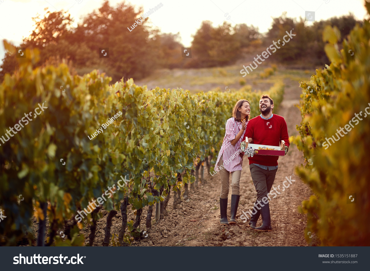 Wine and grapes. Smiling Man and woman winemakers walking in between rows of vines. #1535151887