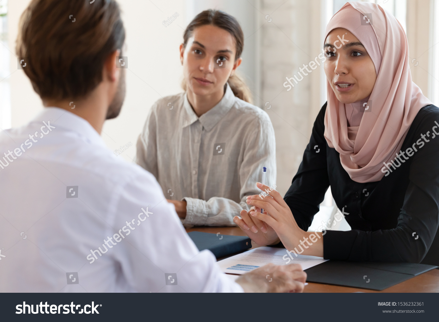 Asian muslim female hr manager interviewing job applicant consulting male client at diverse group meeting negotiations, ethnic businesswoman wear hijab speaking to partner, human resource concept #1536232361