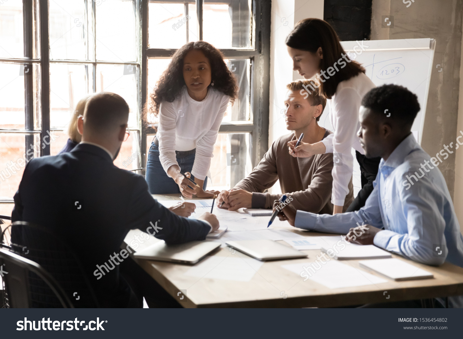 Serious international diverse business team people and african female leader boss discuss financial result review paperwork share ideas brainstorm collaborate work in teamwork at group briefing table #1536454802