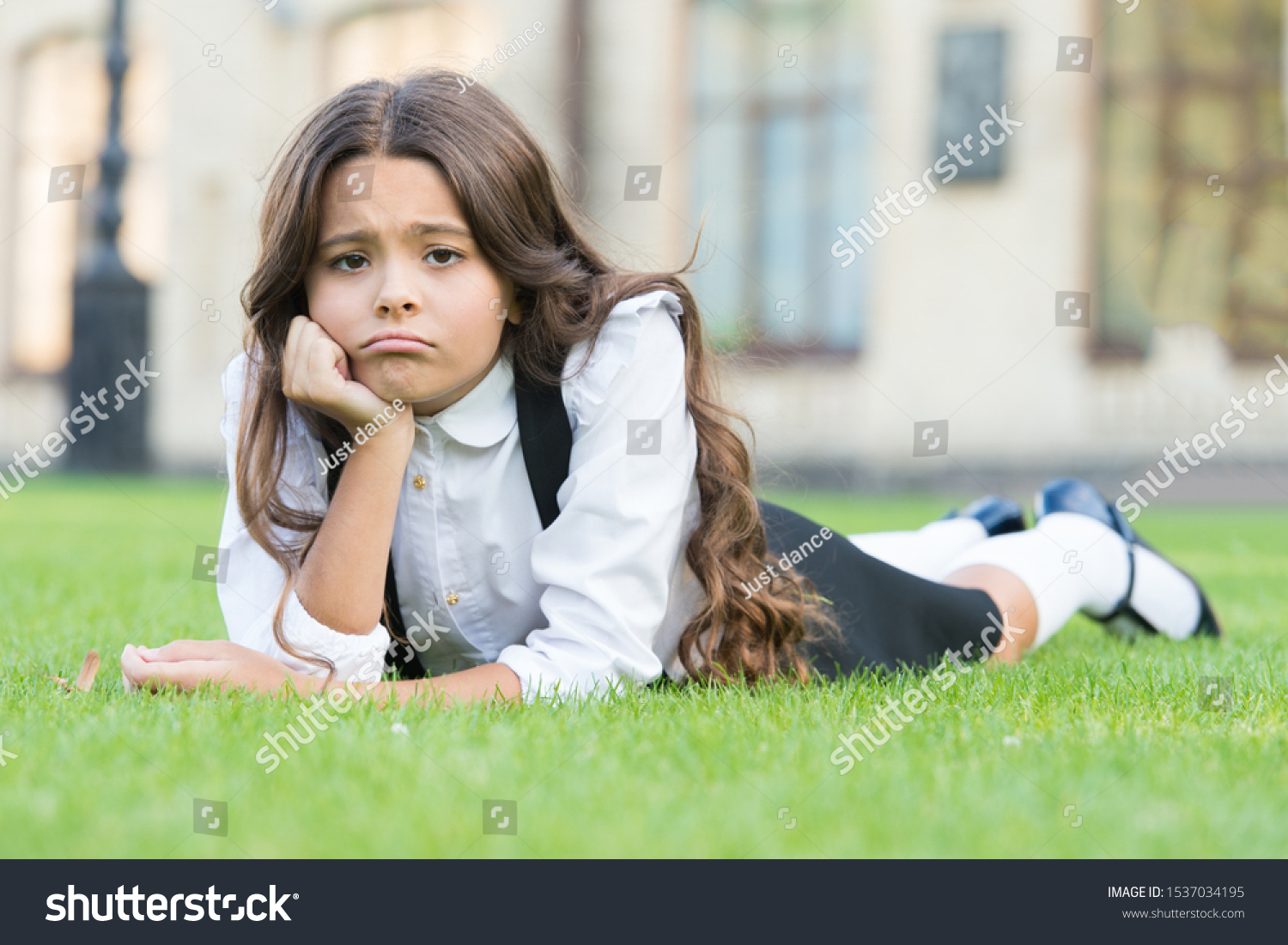 Sad without a smile. Sad schoolgirl relax on green grass. Adorable little child with sad emotion on face. Feeling sad and unhappy. Sadness and depression. School problems. #1537034195