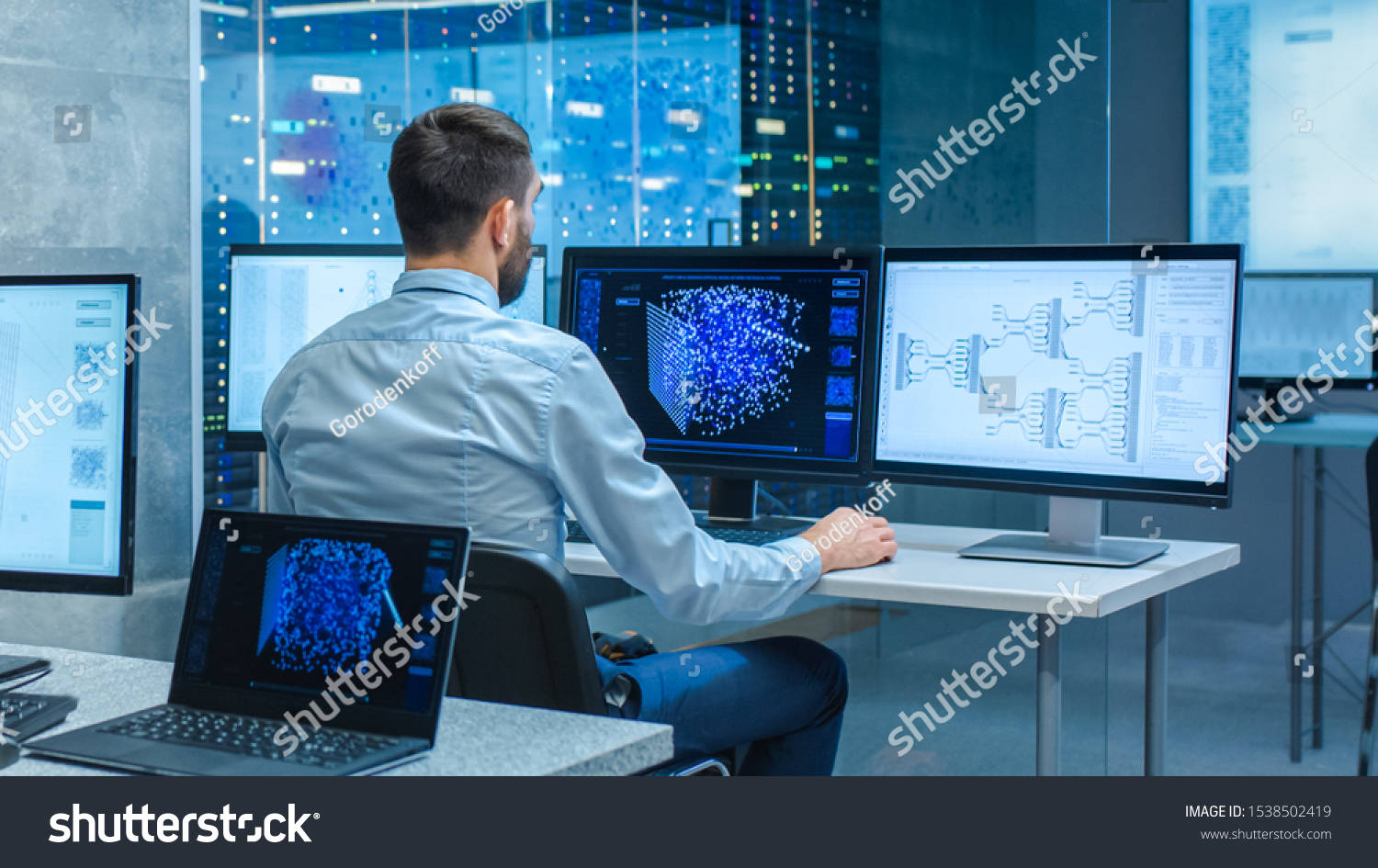 Beautiful Male Computer Engineer and Scientists Create Neural Network at His Workstation. Office is Full of Displays Showing 3D Representations of Neural Networks. #1538502419