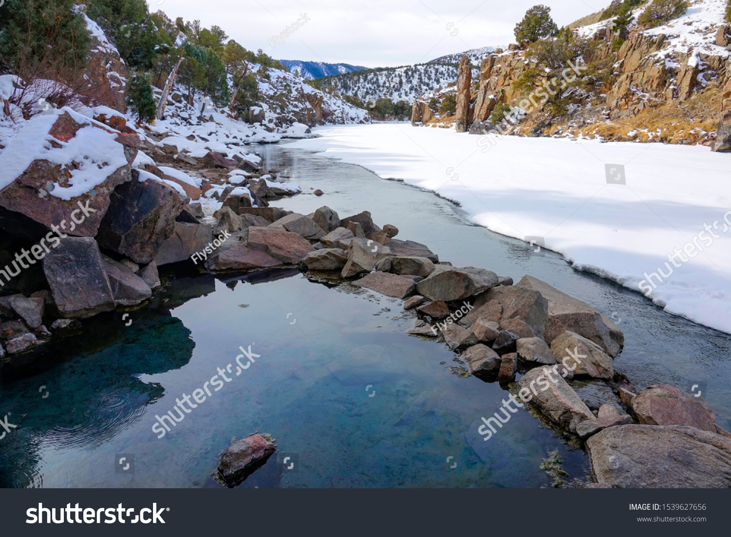 CLOSE UP: Picturesque view of an emerald colored natural hot bath overlooking the picturesque snowy landscape of Colorado. Gorgeous wintry nature surrounds the Radium Hot Springs. Beautiful scenery #1539627656