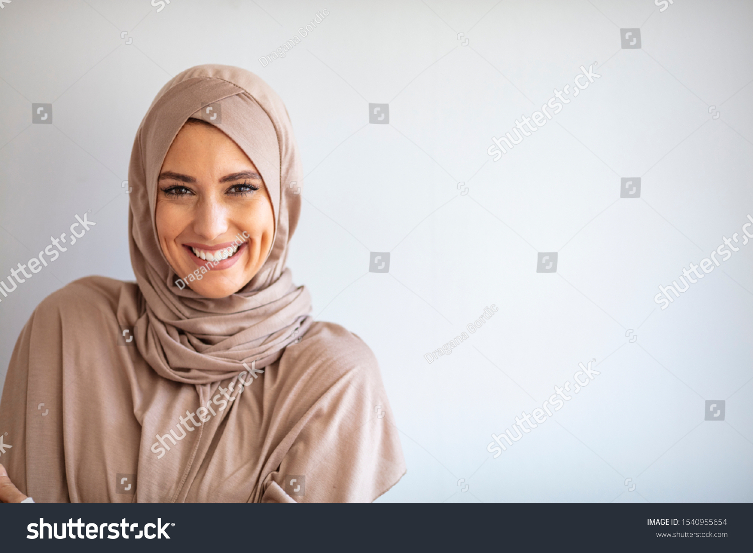Modern, Stylish and Happy Muslim Woman Wearing a Headscarf. Arab saudi emirates woman covered with beige scarf. "Welcome" Face. One women smile with white background  #1540955654