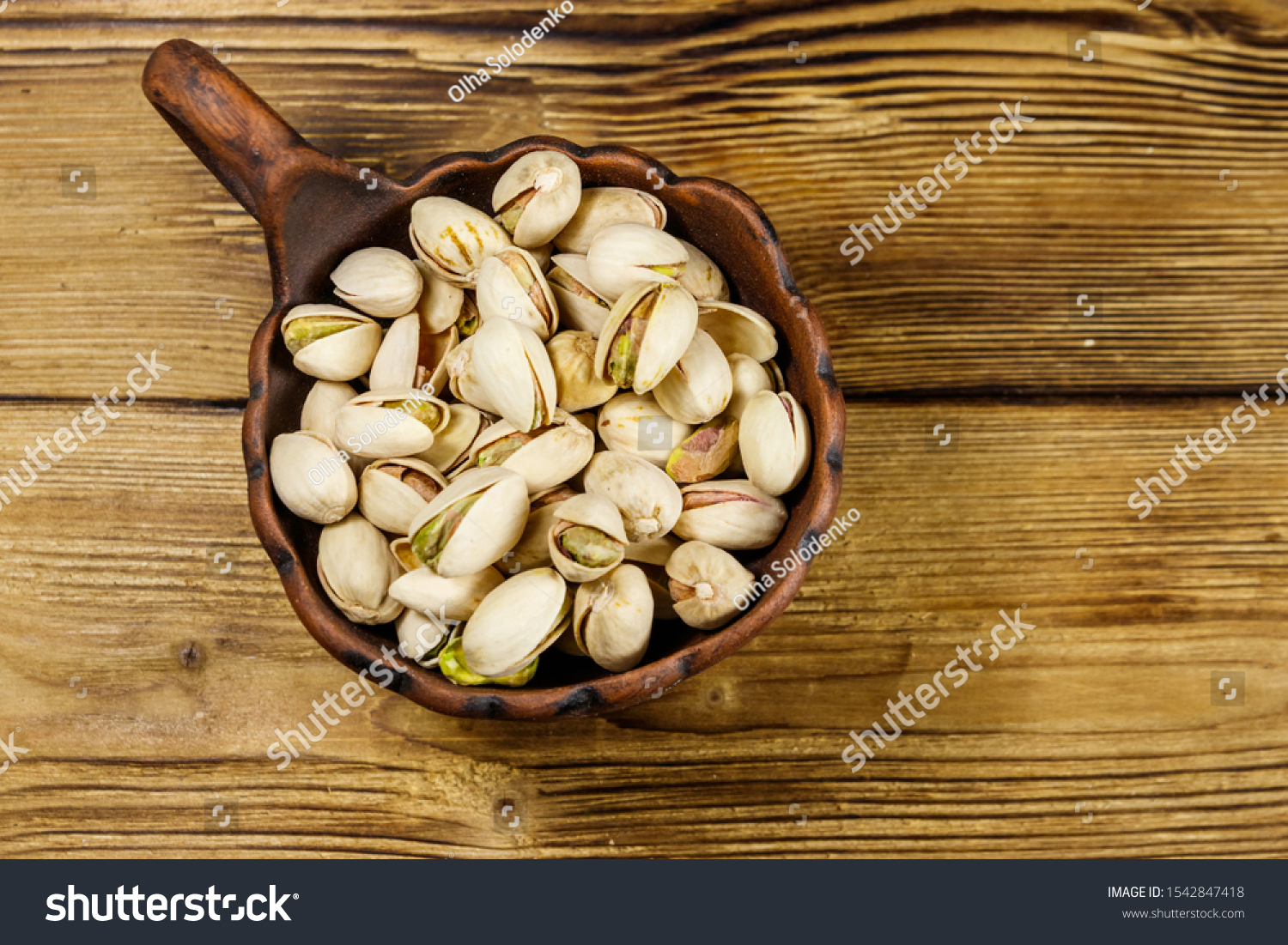 Pistachio nuts in ceramic bowl on a wooden table. Top view #1542847418