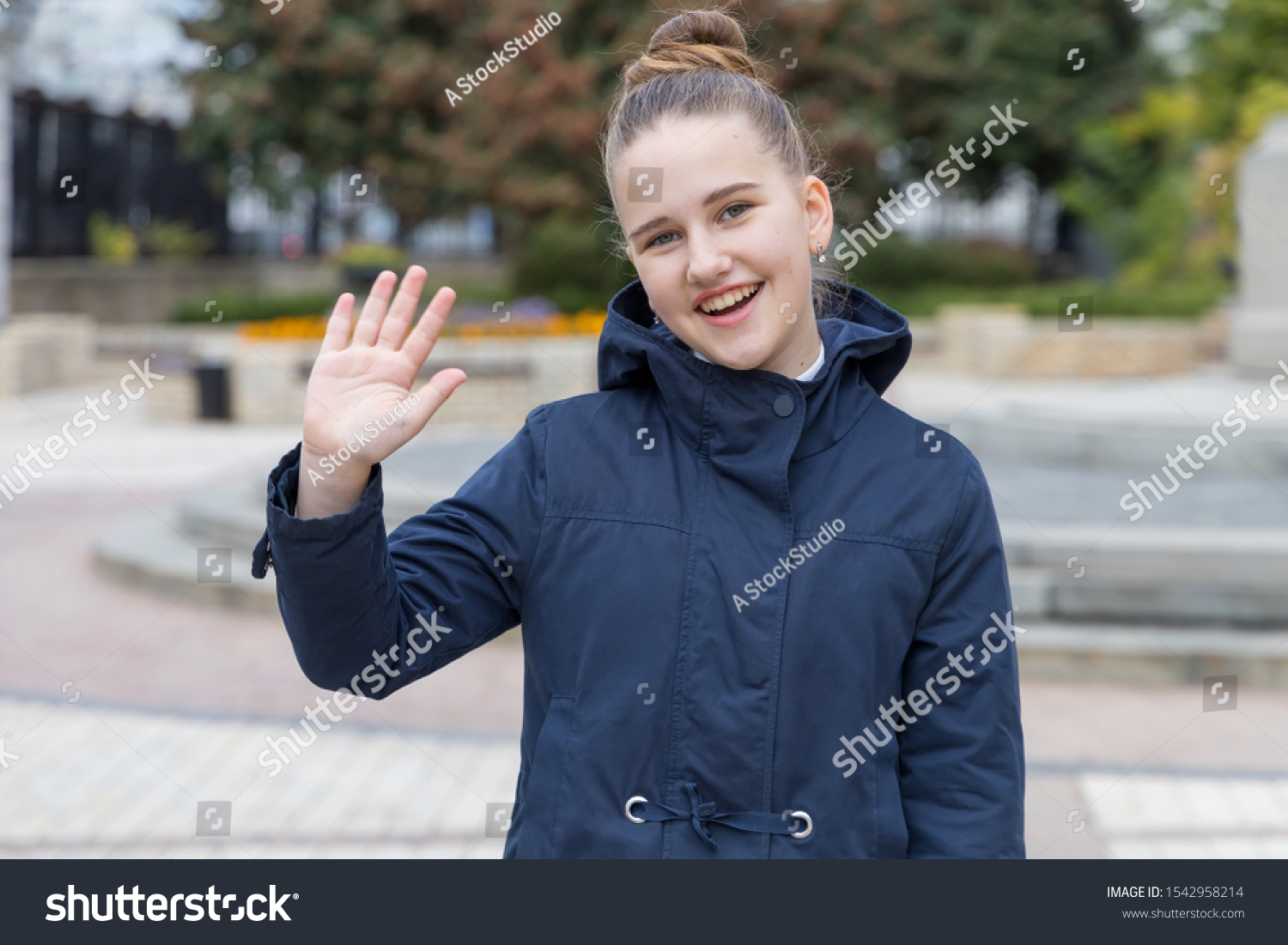 Teenager girl waves her hand, says hello or says goodbye. #1542958214