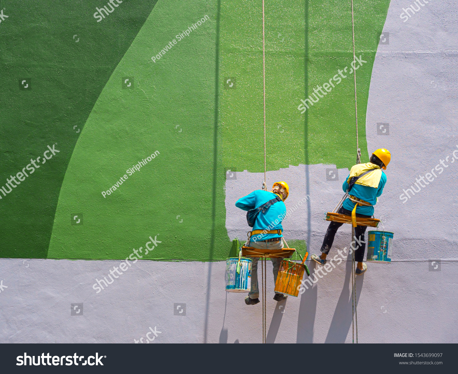 Two painters are painting the exterior of the building on a dangerous looking scaffolding hanging from a tall building with copy space. #1543699097