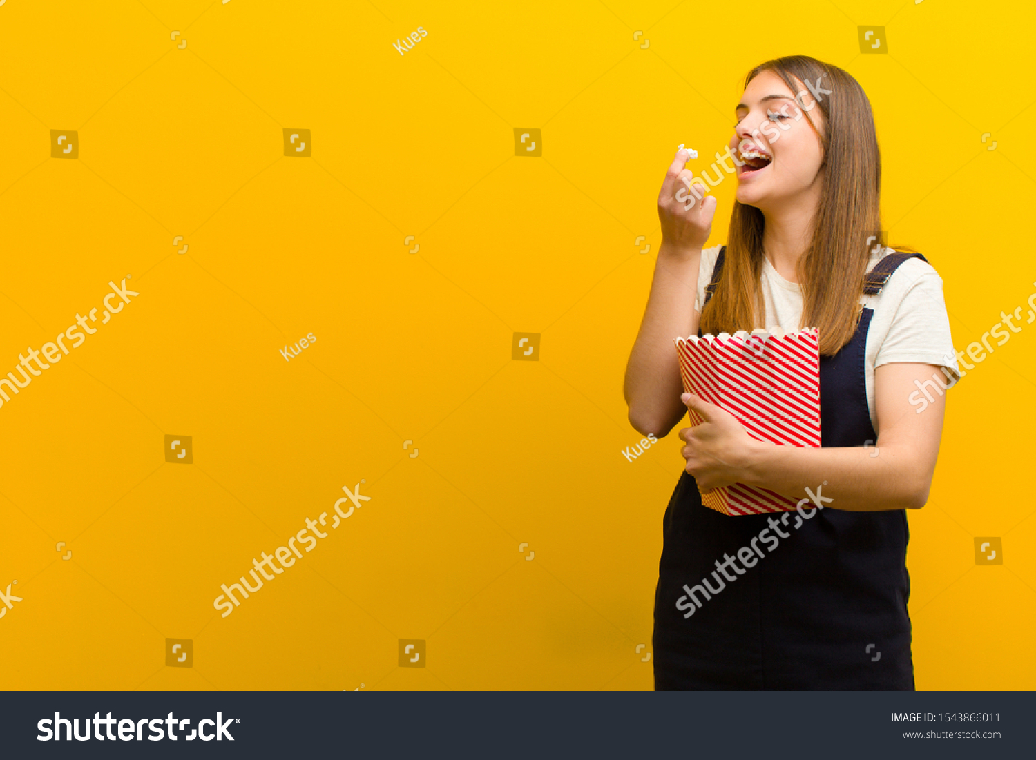 young pretty woman with  pop corns  against orange background #1543866011