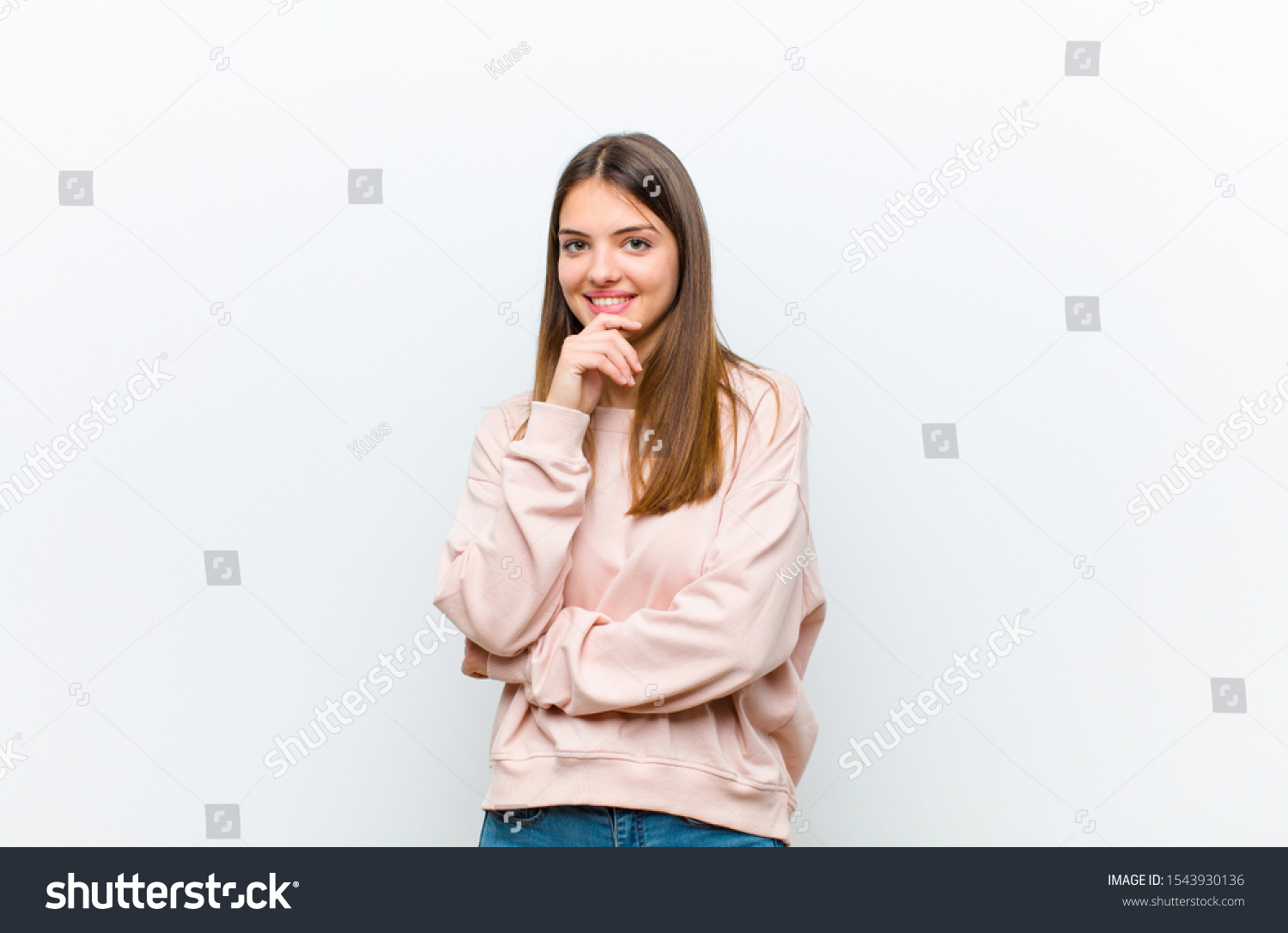 young pretty woman looking happy and smiling with hand on chin, wondering or asking a question, comparing options against white background #1543930136