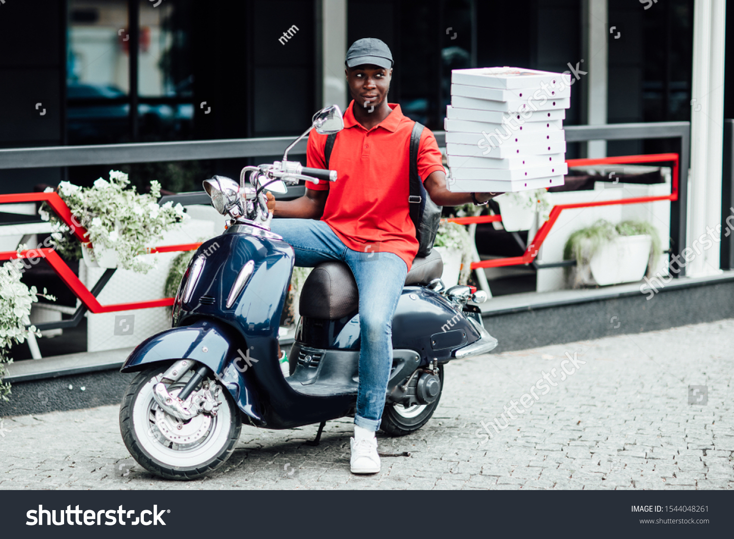 African male courier carries heavy parcel boxes, drives slowly on motorbike, wears protective helmet on head, being specialist in delivery service, distributes fast food, being tired during working da #1544048261