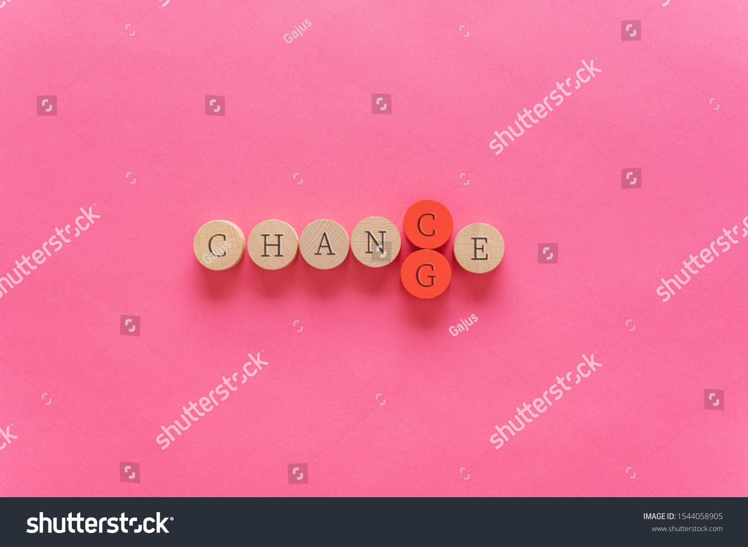 Word Change spelled on wooden cut circles with the word G on red being pushed out with letter C to change the word in Chance. Over pink background with copy space. #1544058905