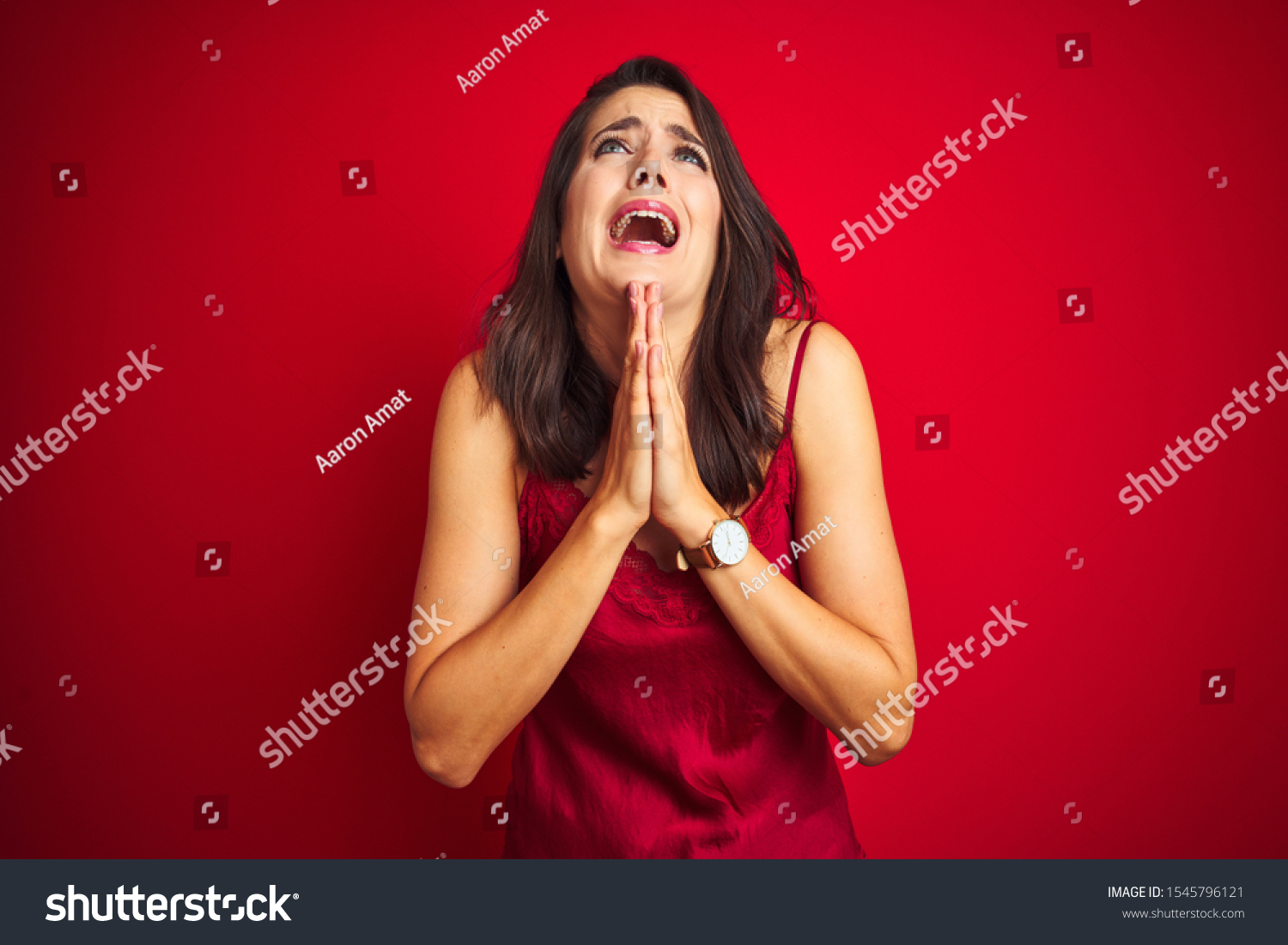 Young beautiful woman wearing sexy lingerie over red isolated background begging and praying with hands together with hope expression on face very emotional and worried. Asking for forgiveness.  #1545796121