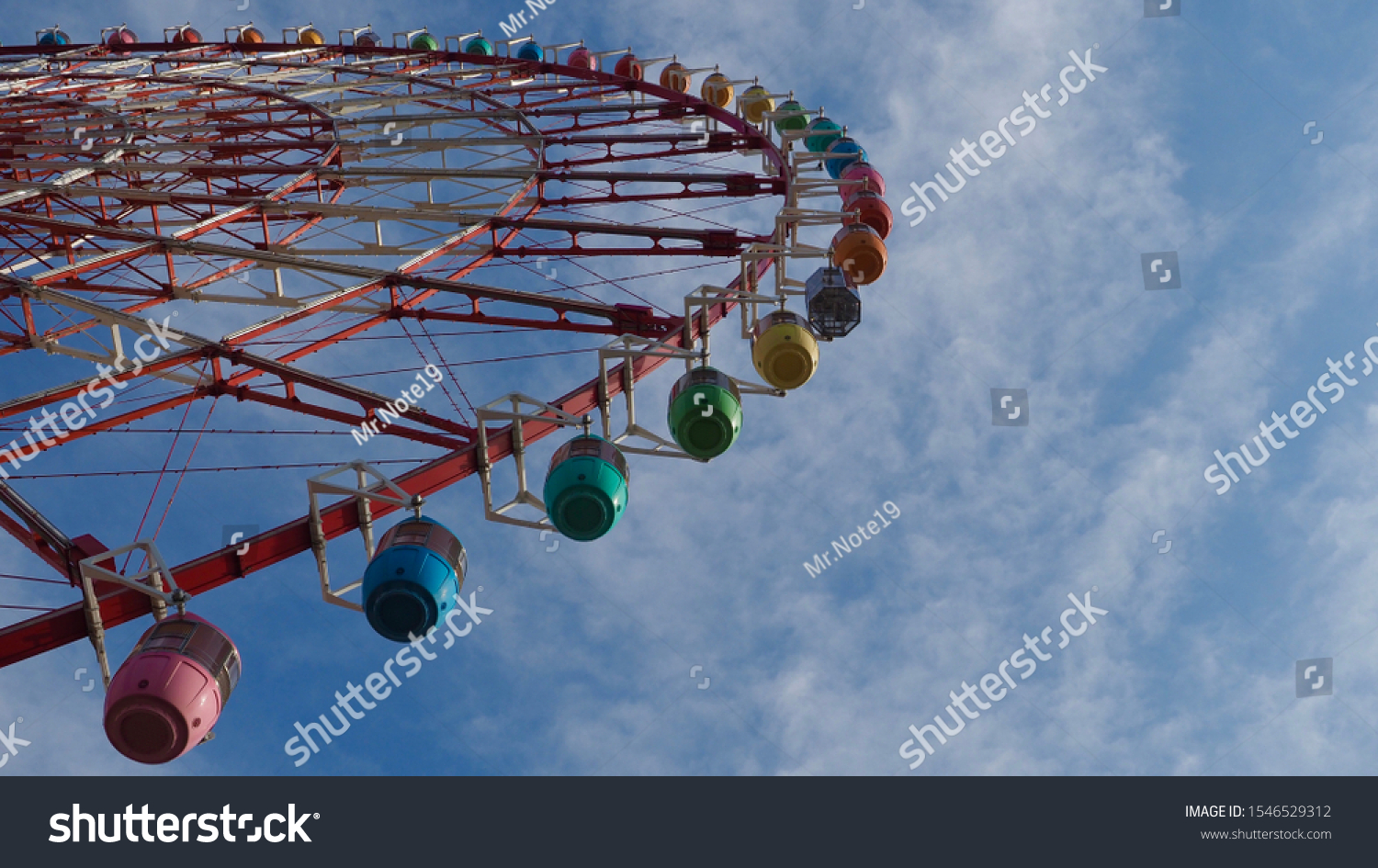 Looking upward to the colorful Ferris wheel in blue sky. #1546529312