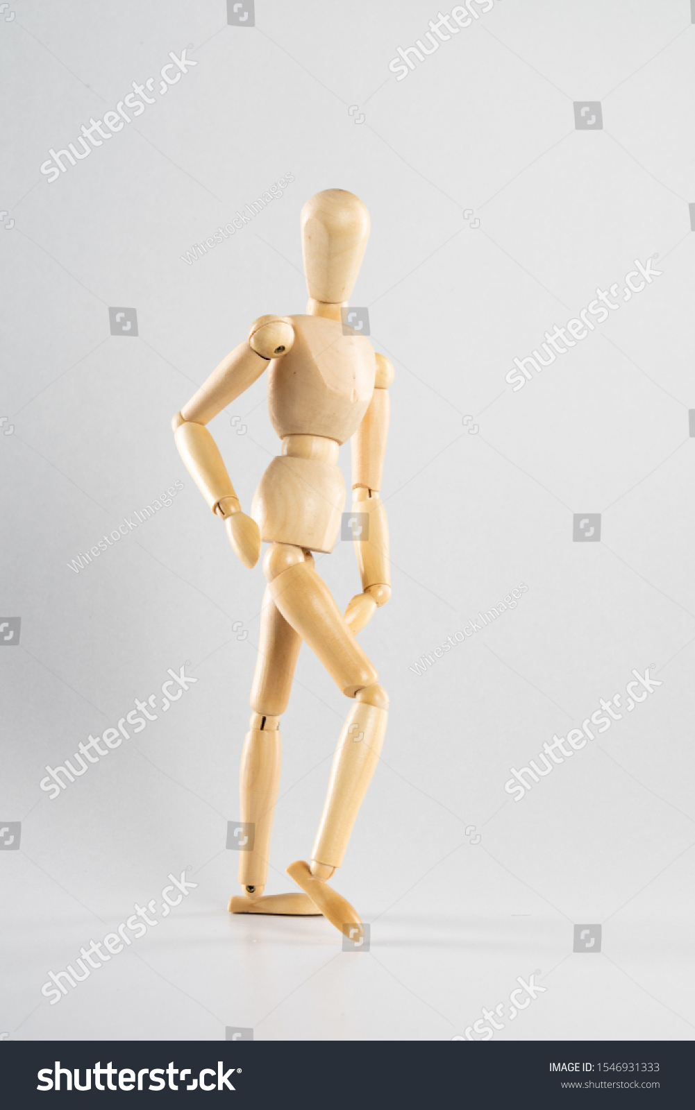 A vertical shot of a wooden pose doll posed like walking  on a white background #1546931333