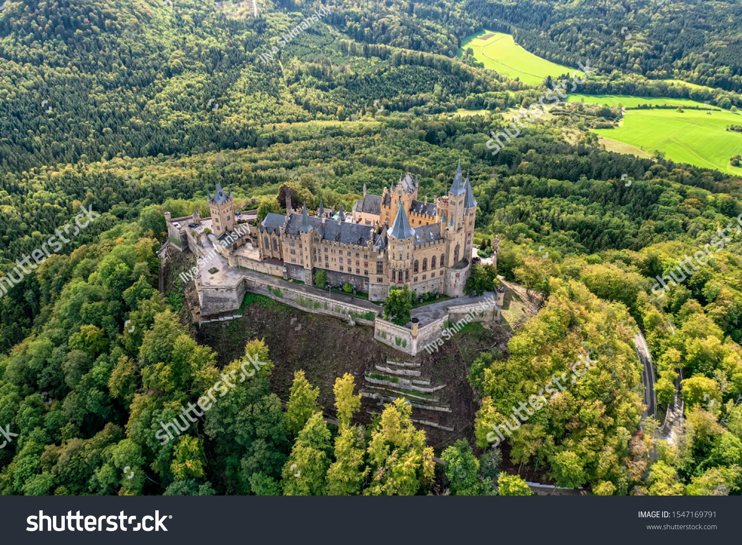 Aerial panorama of Burg Hohenzollern (Hohenzollern castle) with hills and villages surrounded by forests with beautiful foliage #1547169791