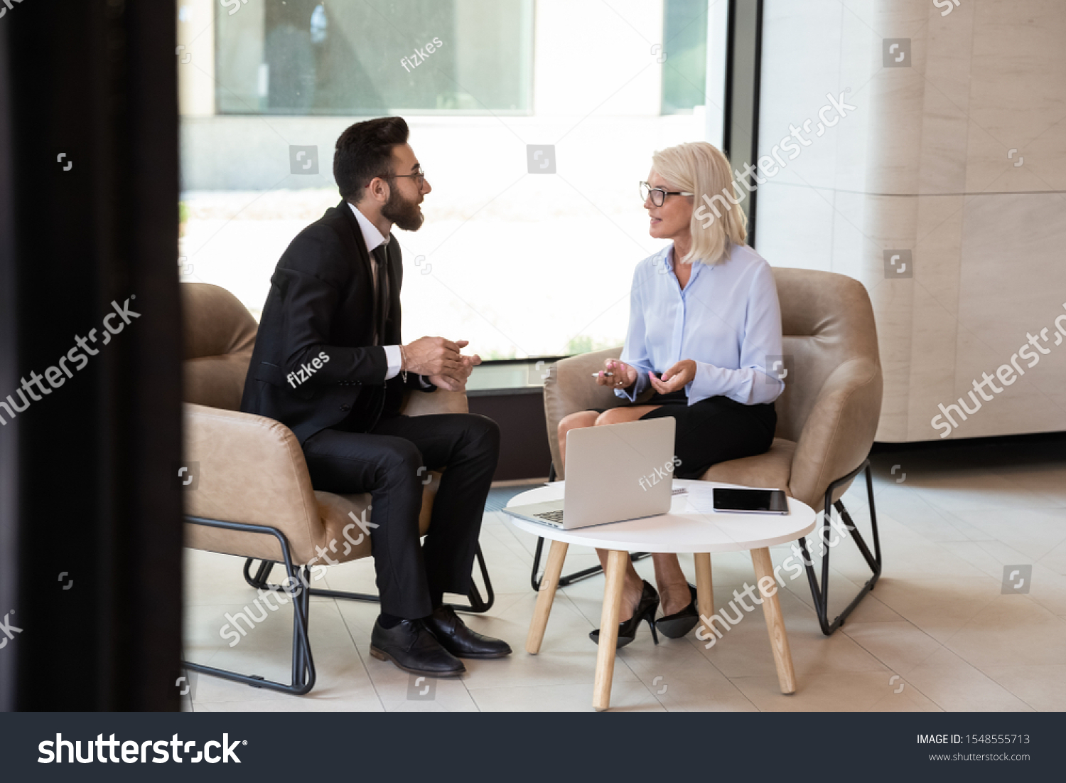 Diverse international man and woman business partners talk discussing potential cooperation, multiracial colleagues businesspeople speak consider project or idea at office meeting, partnership concept #1548555713
