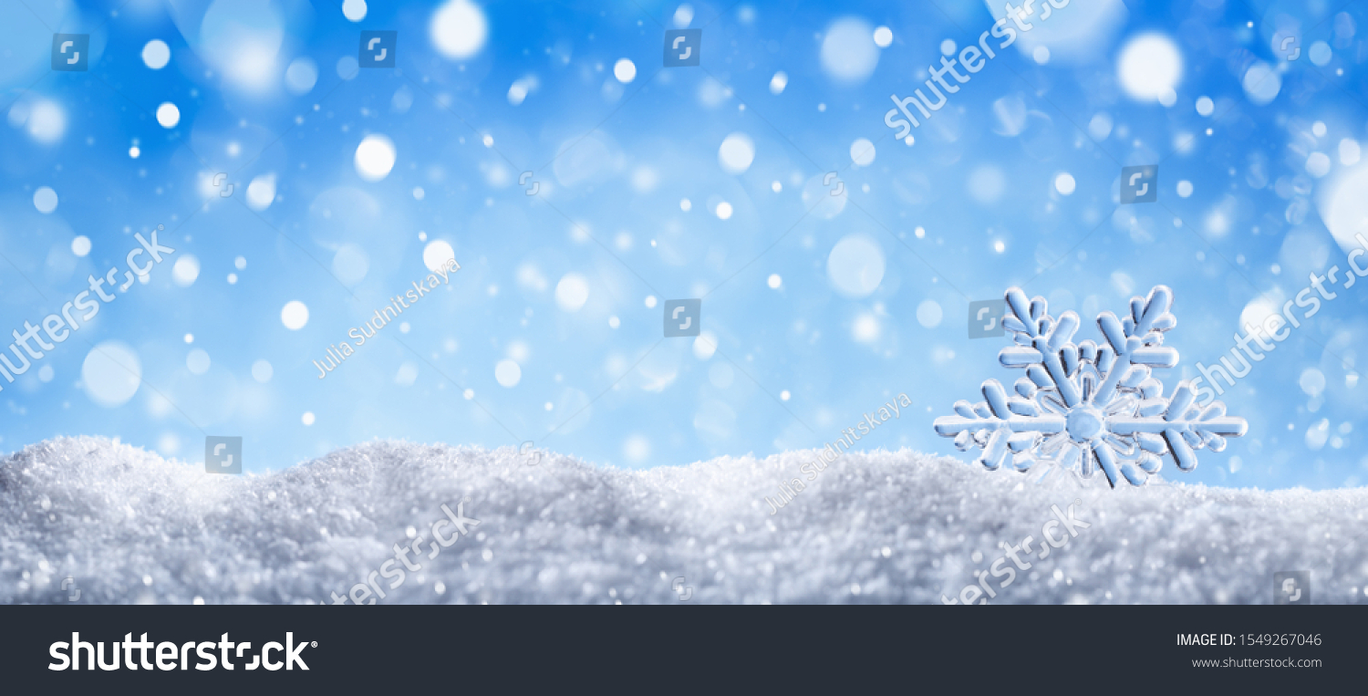 Winter snow background with decorative snowflake against blue sky. Banner format. Beautiful wintertime holiday scene.  #1549267046