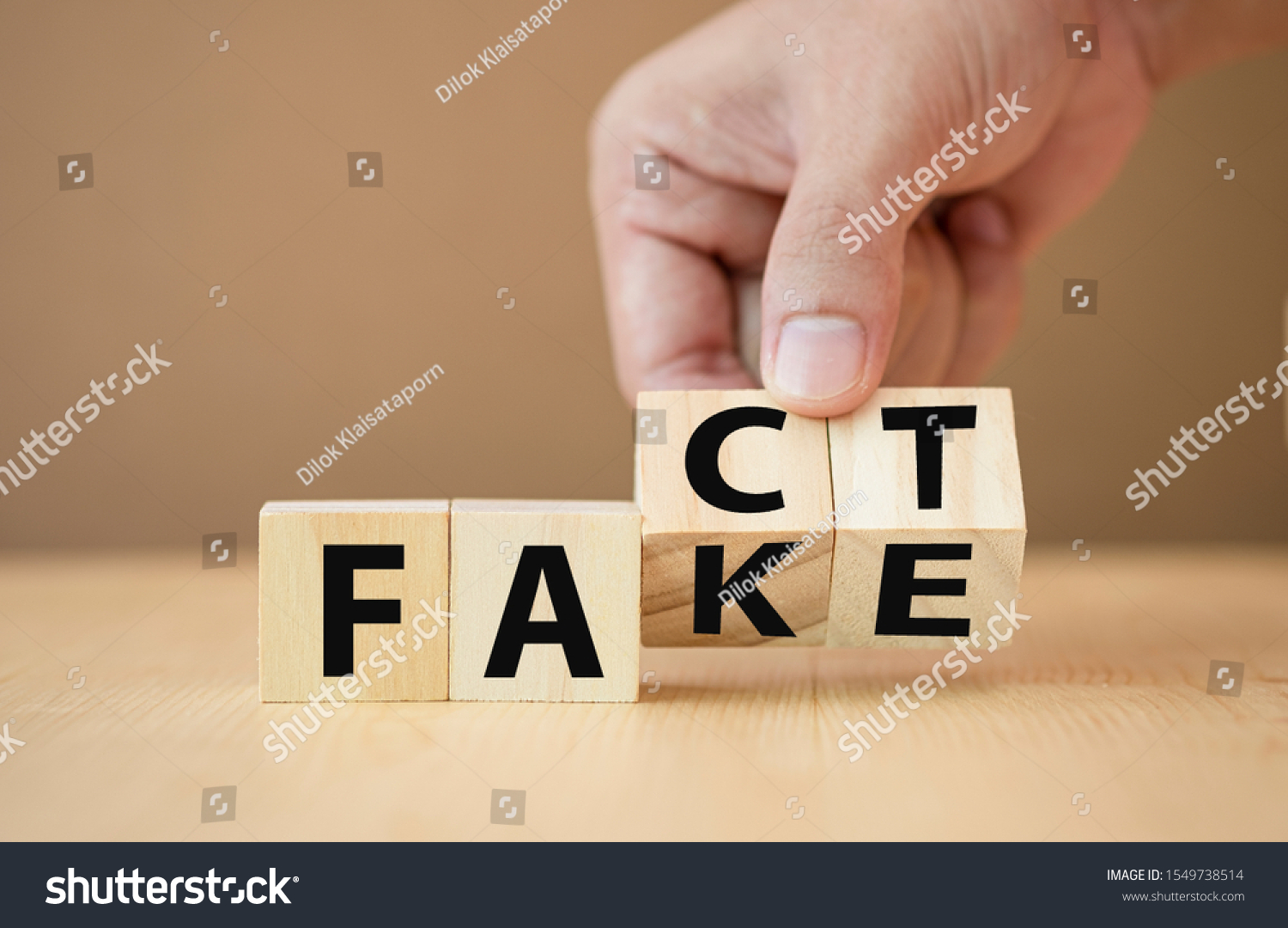 Hand flipping wooden cubes for change wording from "fake" to "fact". #1549738514