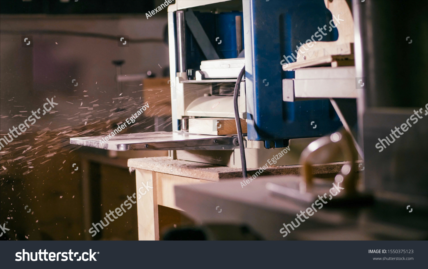 Cabinet planer machine is working with sawdust at wood workshop . Process of work surf gage machine #1550375123