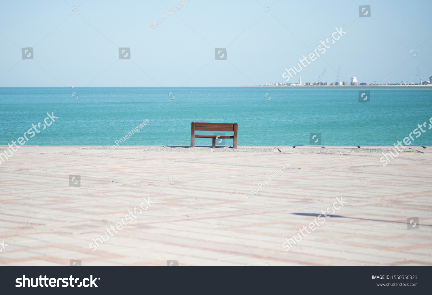 An empty chair along the Corniche or the boardwalk overlooking the sea or the bay in Doha Qatar #1550550323