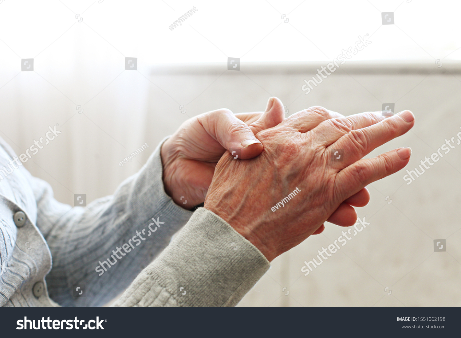Elderly woman applying moisturizing lotion cream on hand palm, easing aches. Senior old lady experiencing severe arthritis rheumatics pains, massaging, warming up arm. Close up, copy space, background #1551062198