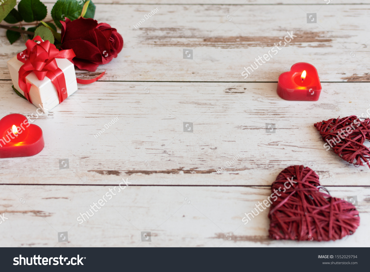 Red roses with hearts and candles on wooden background. St. Valentines Day or Wedding card concept with copy space for your text. #1552029794