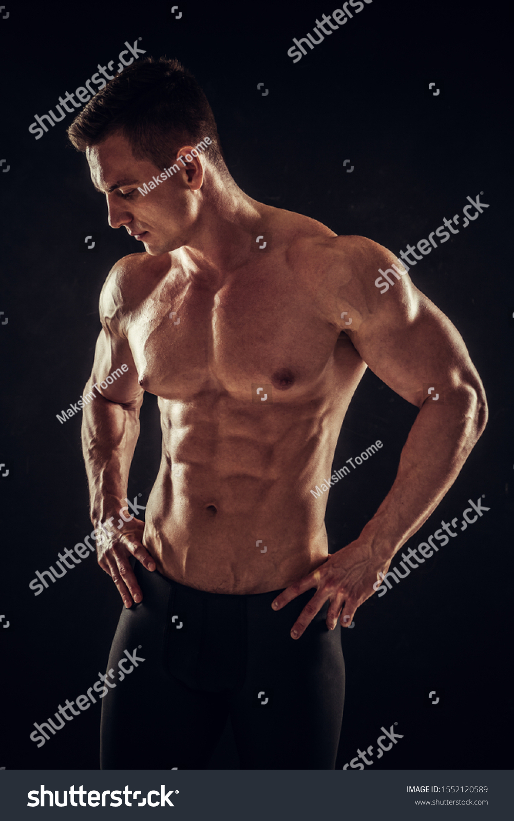 Handsome athletic man showing his trained body on dark background #1552120589