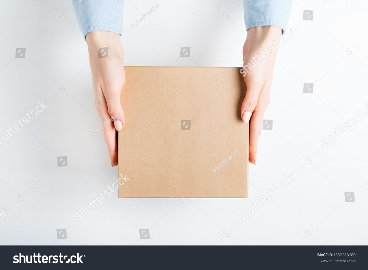 Square cardboard box in female hands. Top view, white background #1552283660