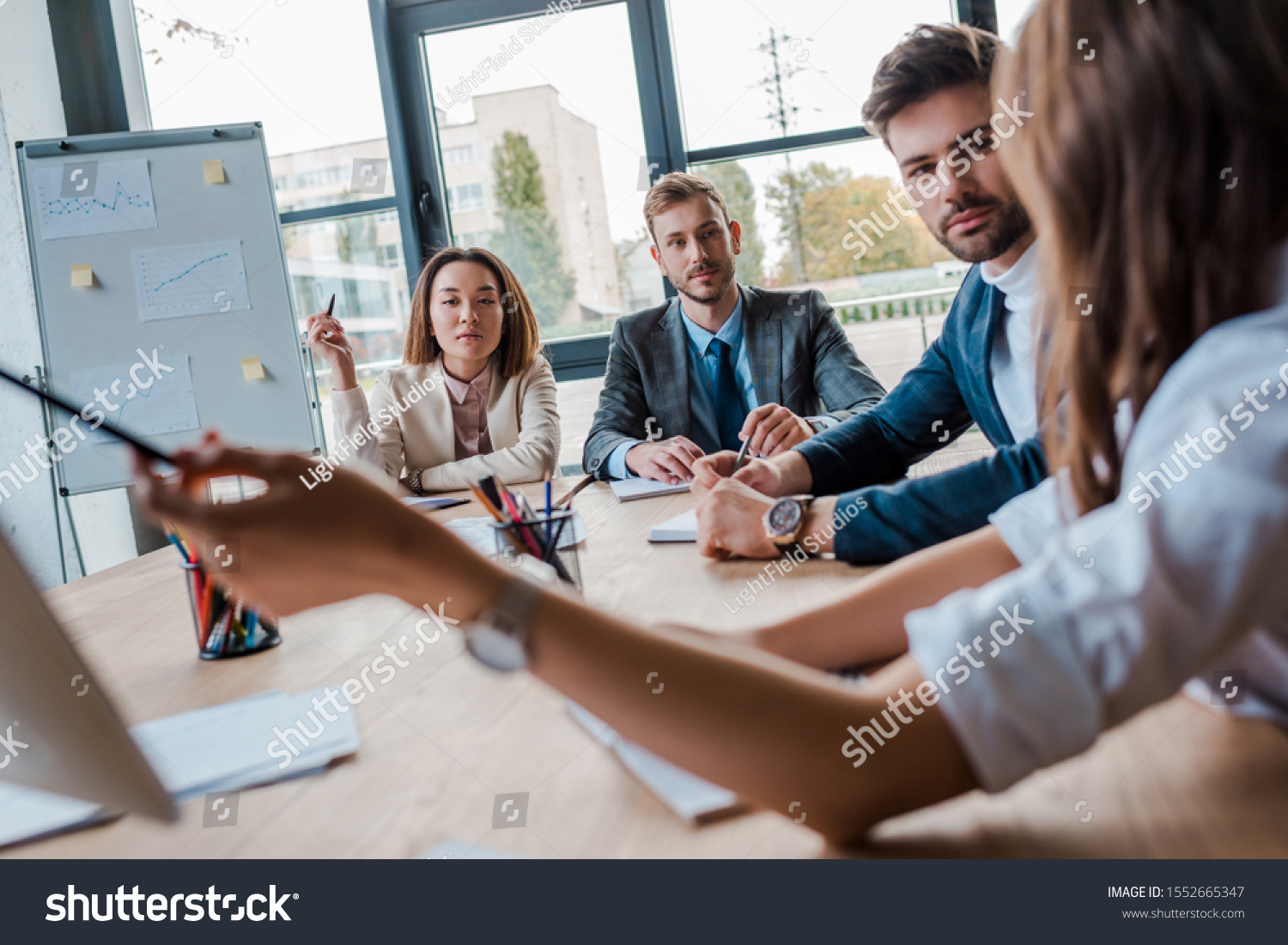 selective focus of multicultural businesspeople looking at coworker in office  #1552665347