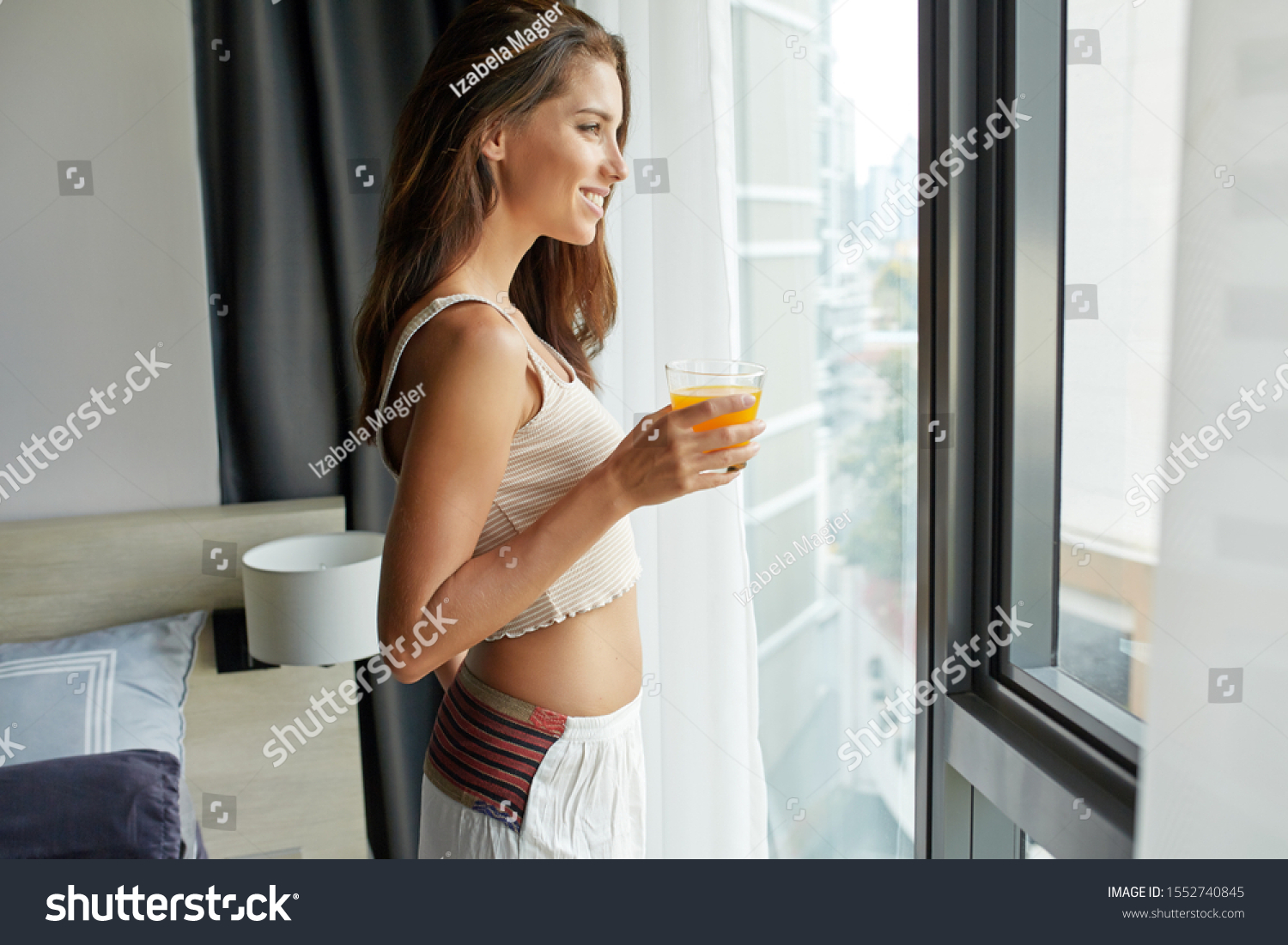 A woman relaxes in the bedroom and drinks orange juice #1552740845