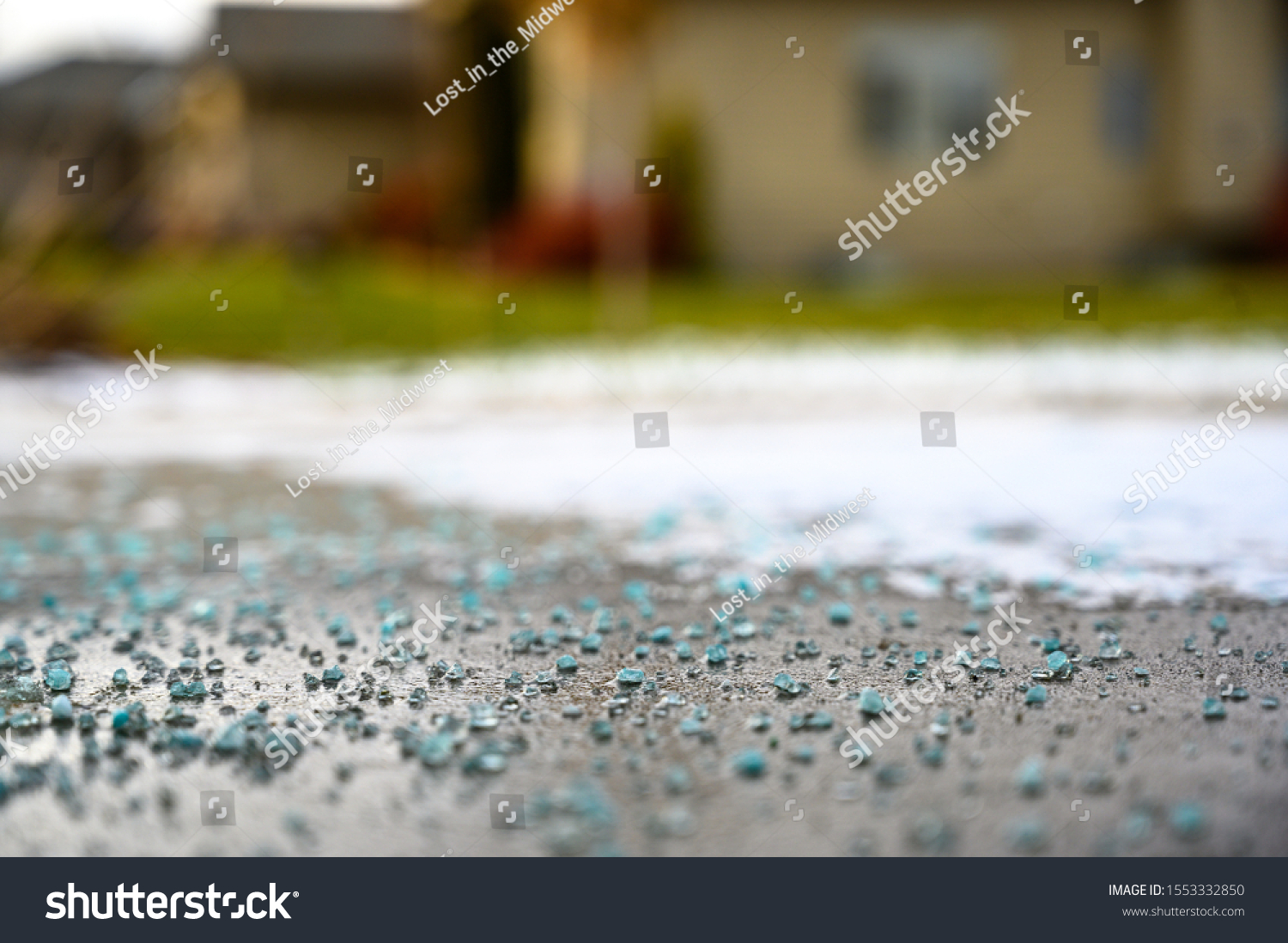 Ground level closeup view of rock salt ice-melt  on concrete with snow #1553332850