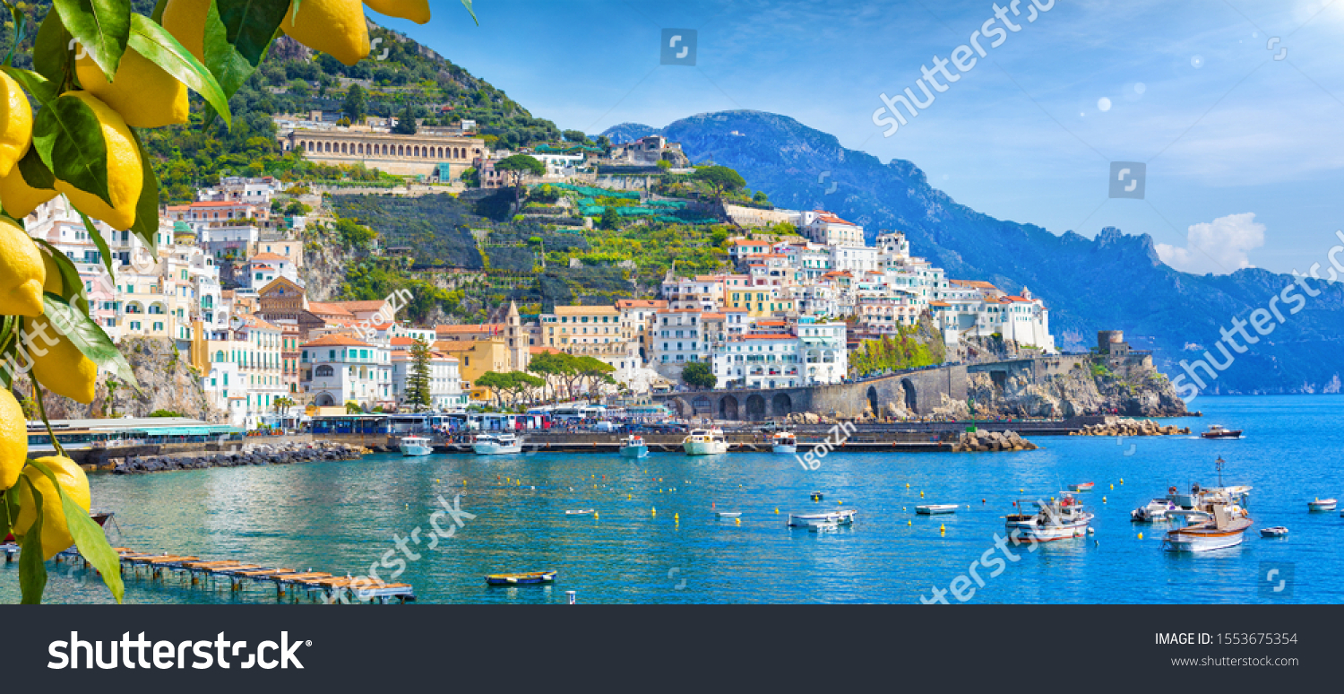 Panoramic view of beautiful Amalfi on hills leading down to coast, Campania, Italy. Amalfi coast is most popular travel and holiday destination in Europe. Ripe yellow lemons in foreground. #1553675354