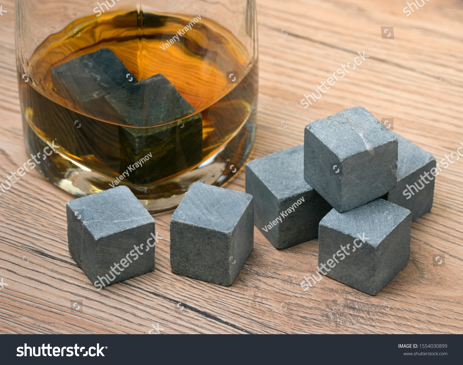 Glass with whiskey and whiskey stones on wooden background #1554030899