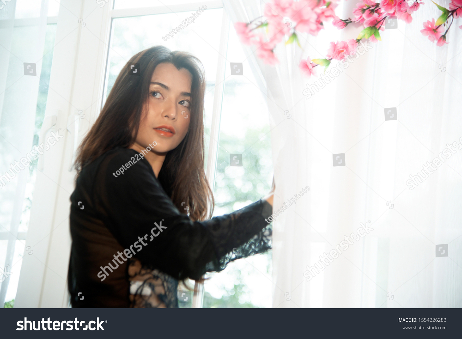 Sensual sexy dresses Asian women sensuality standing under pink flower tree near window.   #1554226283