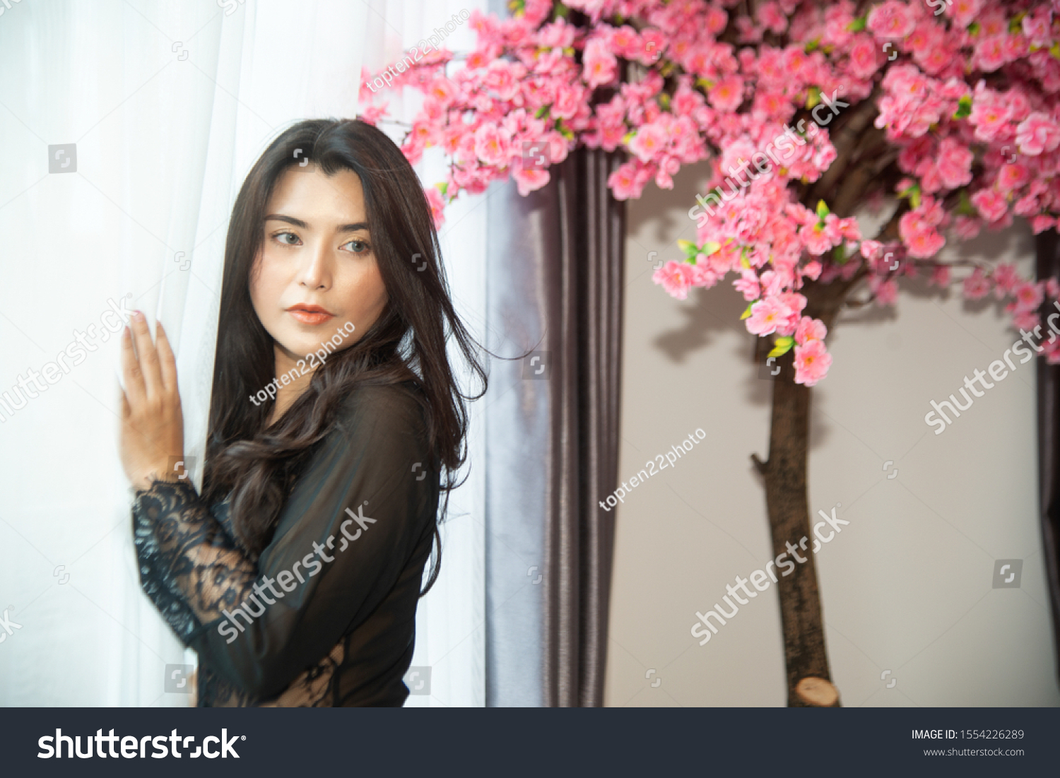 Sensual sexy dresses Asian women sensuality standing under pink flower tree near window.   #1554226289