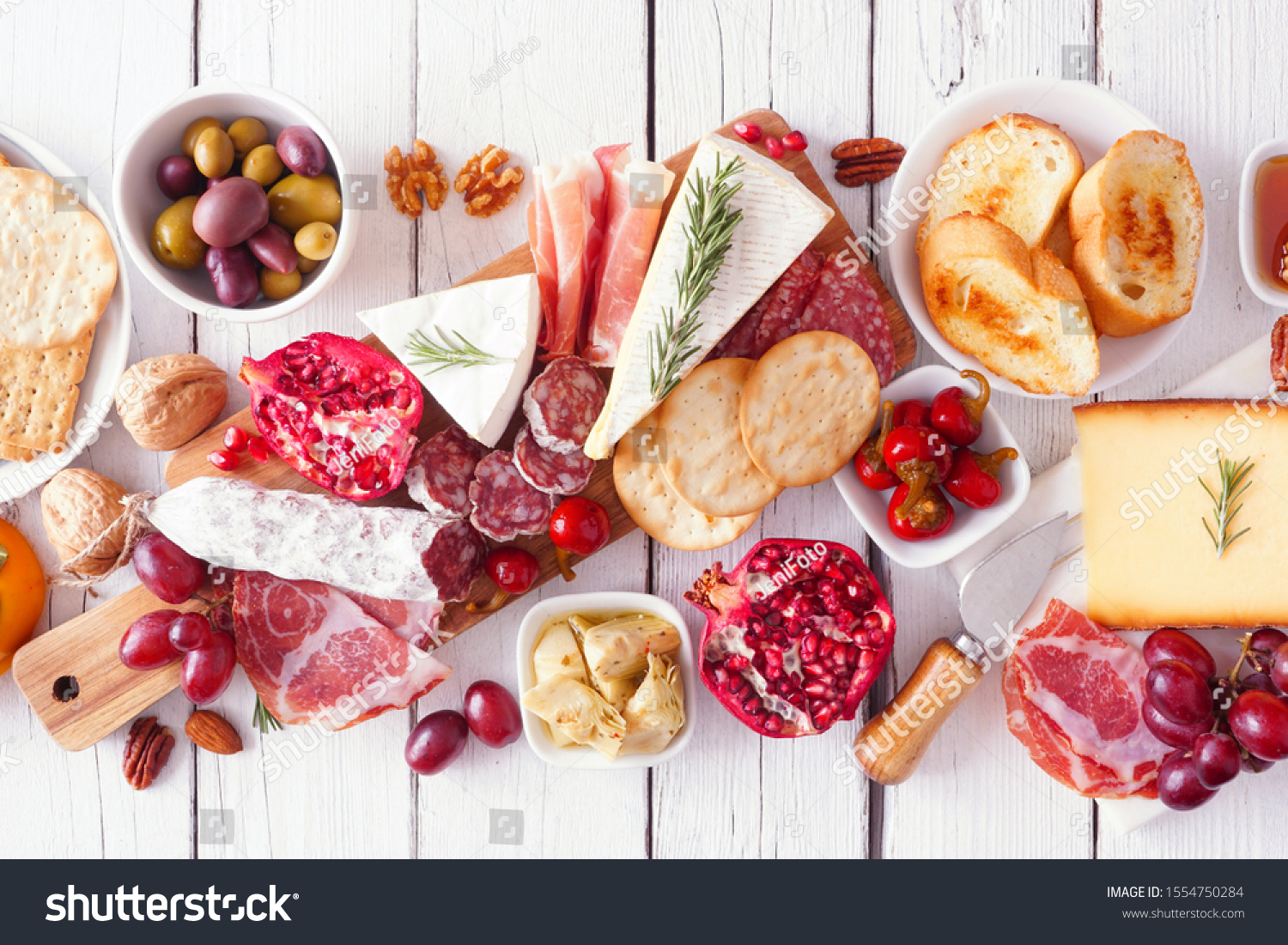 Charcuterie board of assorted cheeses, meats and appetizers. Above view table scene on a white wood background. #1554750284