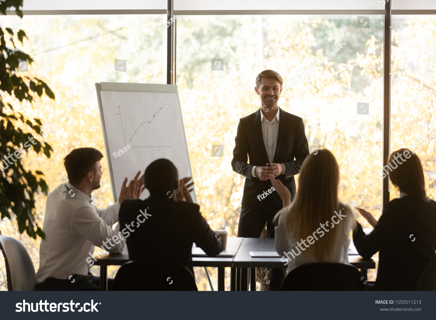 Excited multiethnic diverse employees listeners applaud thank smiling successful male speaker for presentation, happy multiracial colleagues clap hands greeting man presenter, acknowledgment concept #1555511213