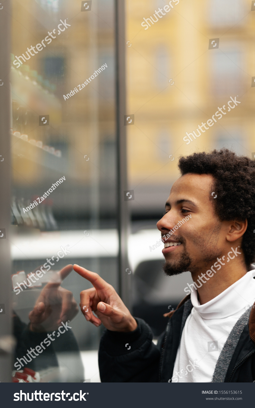 African man buys drink or sweets at vending machine outside. #1556153615
