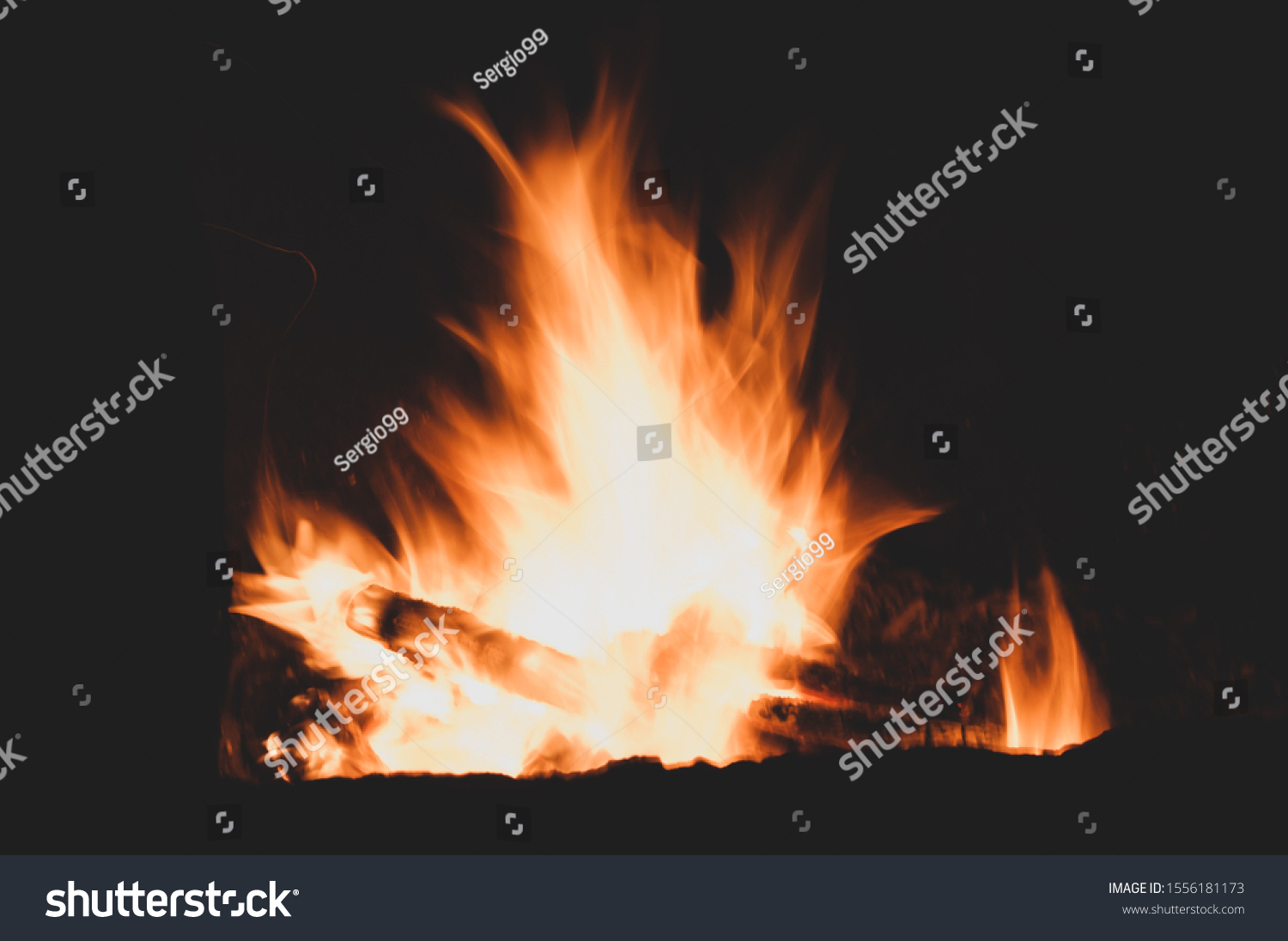 Firewood burns brightly. Light scatters darkness. Bright colorful sparkling flaming warming fire. Burning fire on black background close-up. Horizontal background #1556181173