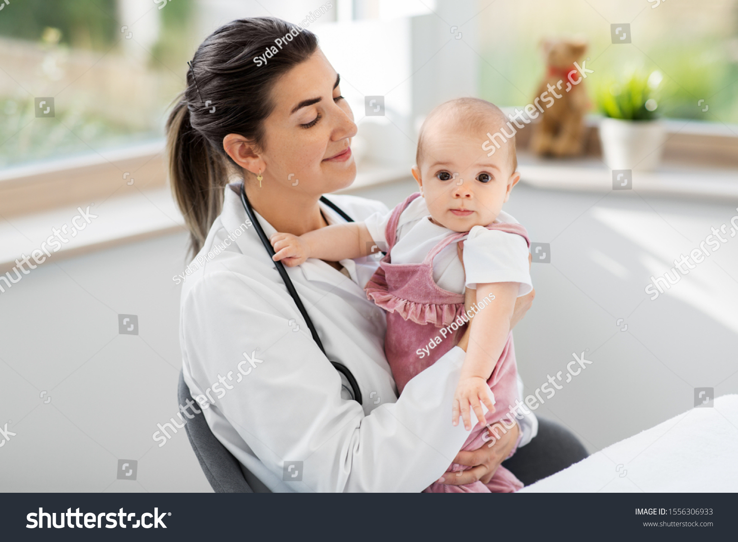 medicine, healthcare and pediatrics concept - smiling female pediatrician doctor or nurse holding baby girl patient at clinic or hospital #1556306933