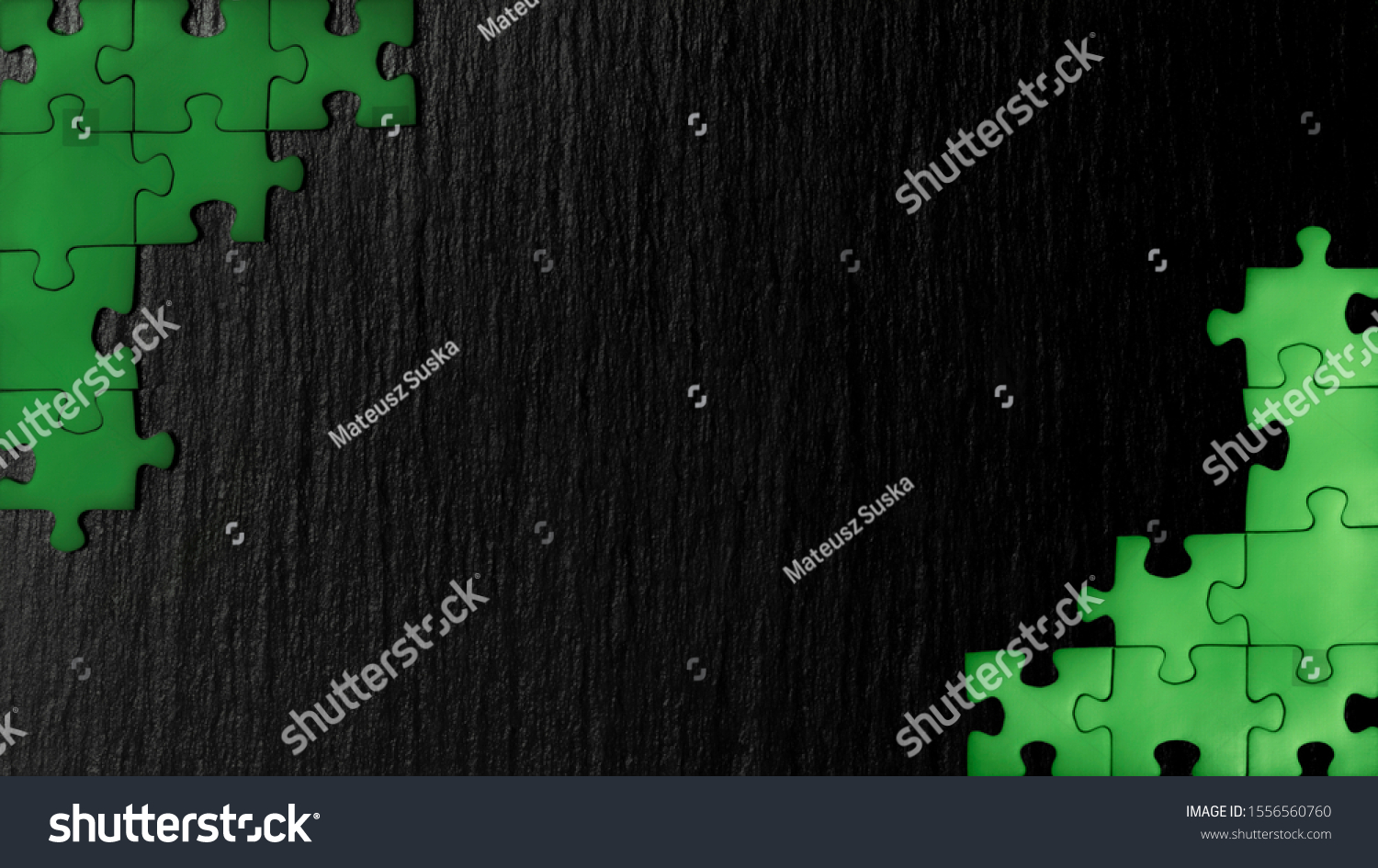 Green puzzle in the corners of the image on a black natural stone background of slate. A frame with an empty space for your description. #1556560760