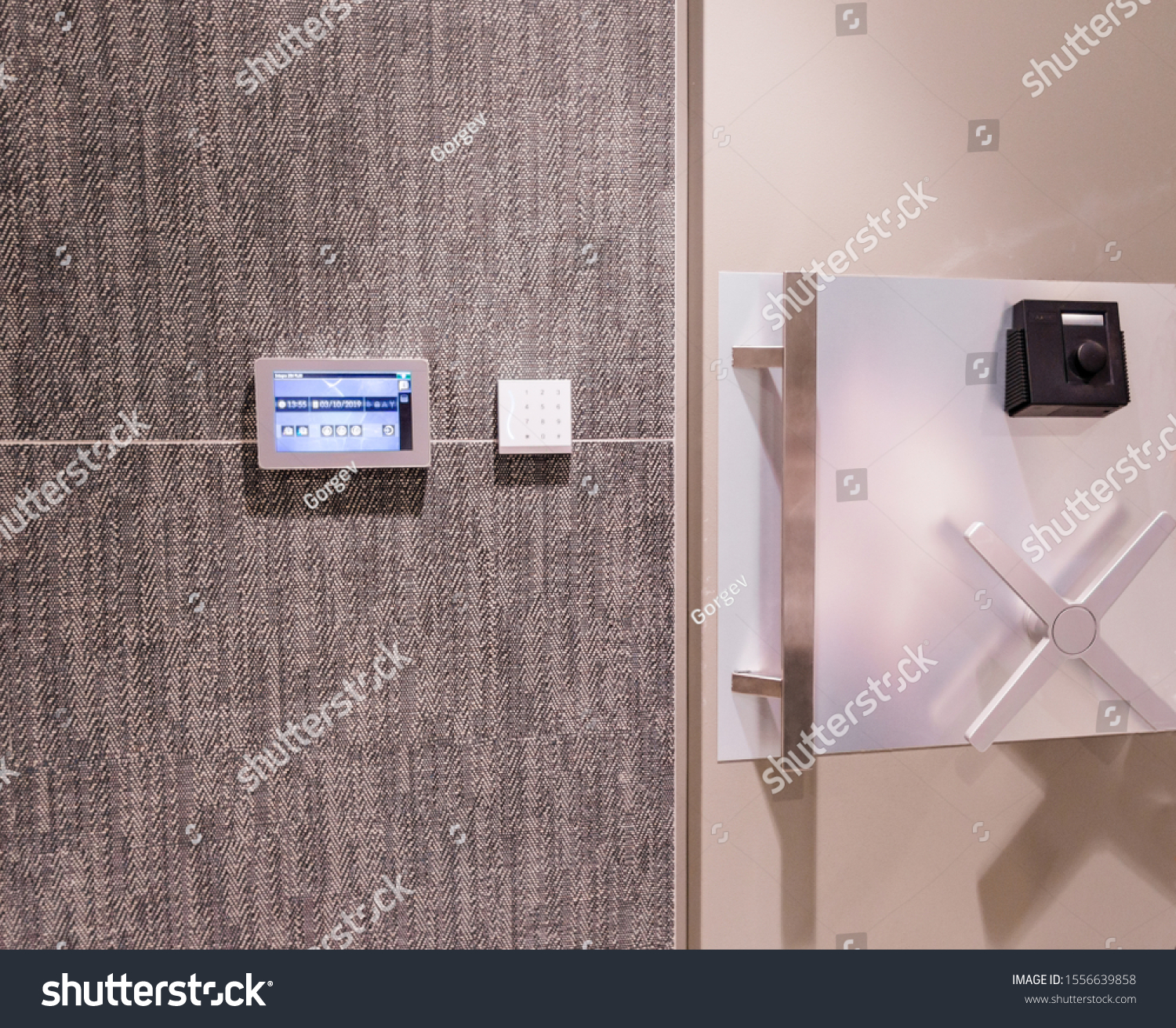 Security woman in uniform standing infront of safe door with keypad and touchscreen #1556639858