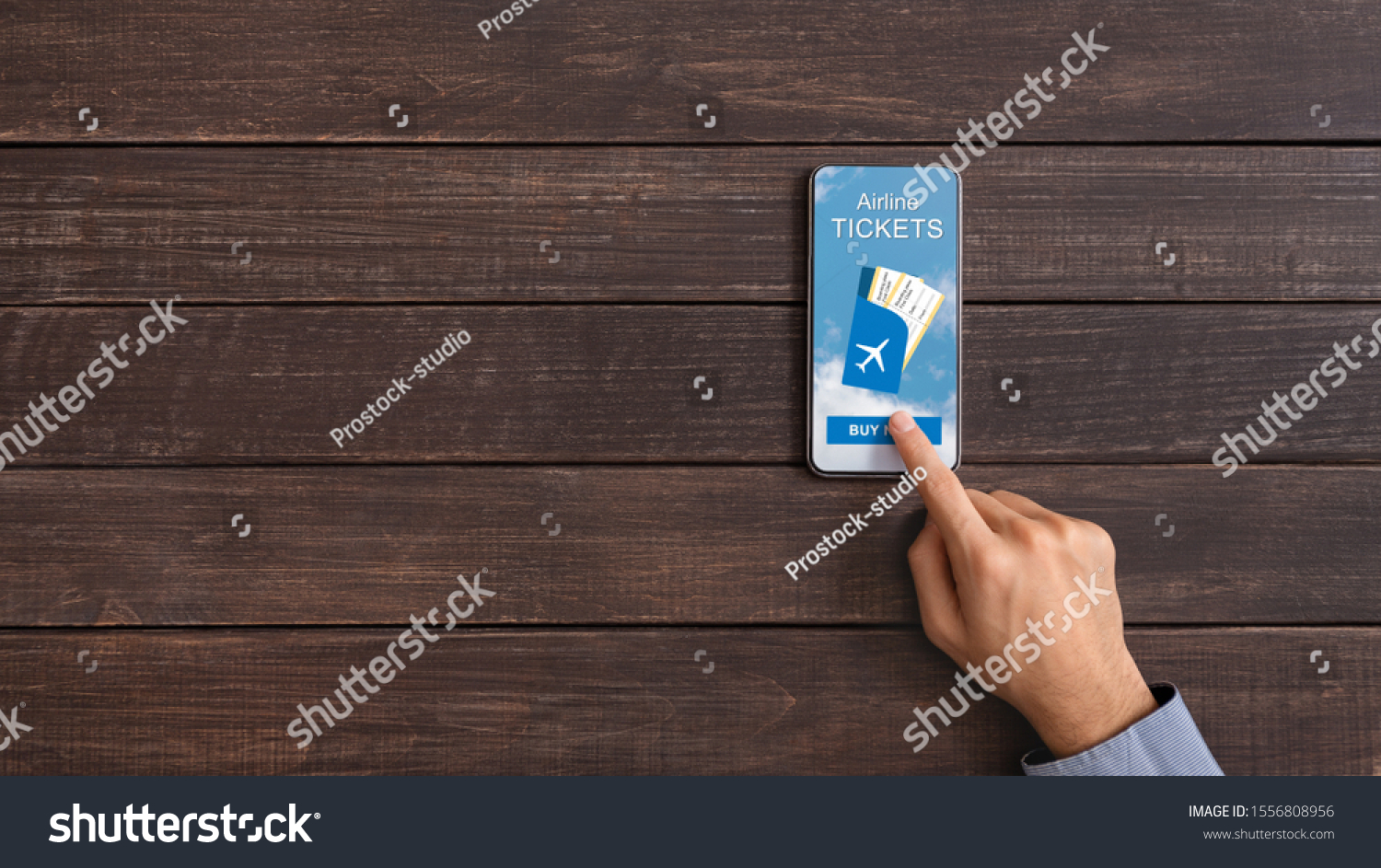 Book your flight. Man downloading application for purchasing airline tickets online on smartphone, panorama with free space on wooden background #1556808956