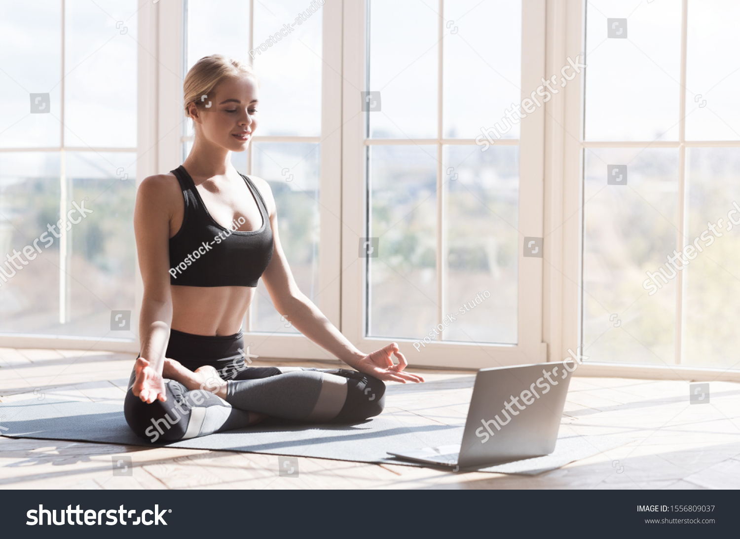 Sport application, website. Cheerful young woman practicing yoga at home, using laptop, copy space #1556809037