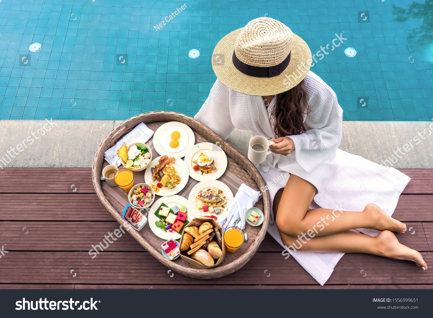 Served floating breakfast in 5 star hotel resort. Pretty young woman enjoying breakfast in the pool at luxury villa. Beautiful brunette girl relaxing and drinking coffee #1556999651