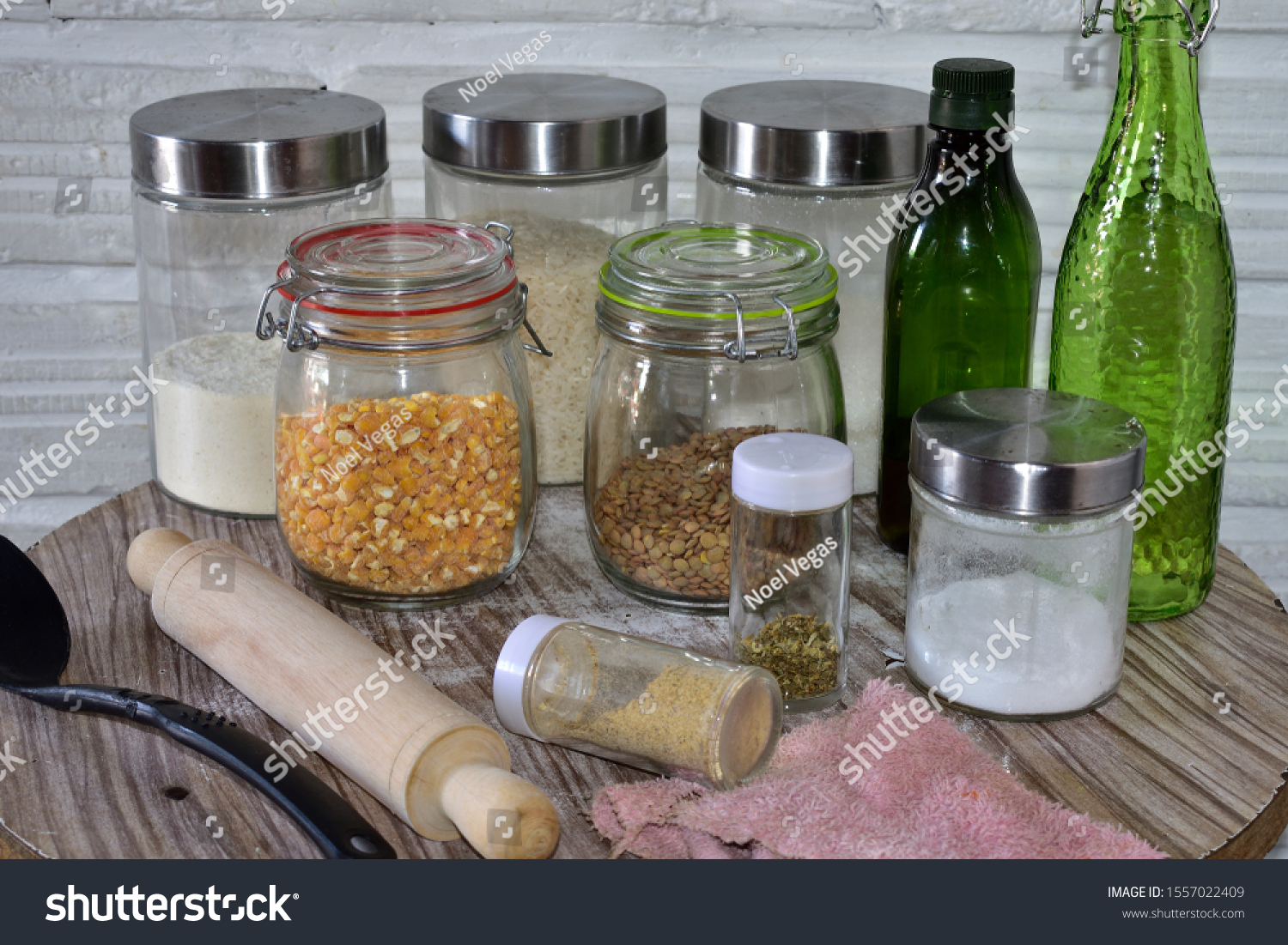 Set of glass cylindrical kitchen containers on a wooden table with cereals a spoon and a rolling pin

 #1557022409