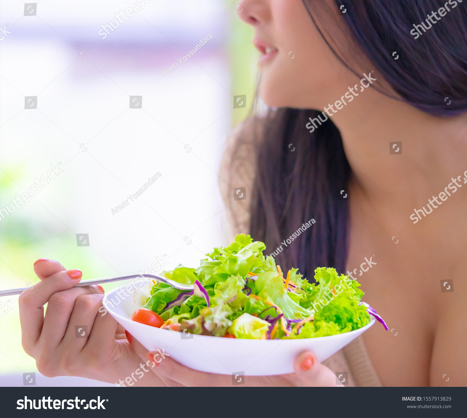 Healthy young woman is eating green salad for healthy lifestyle food concept #1557913829