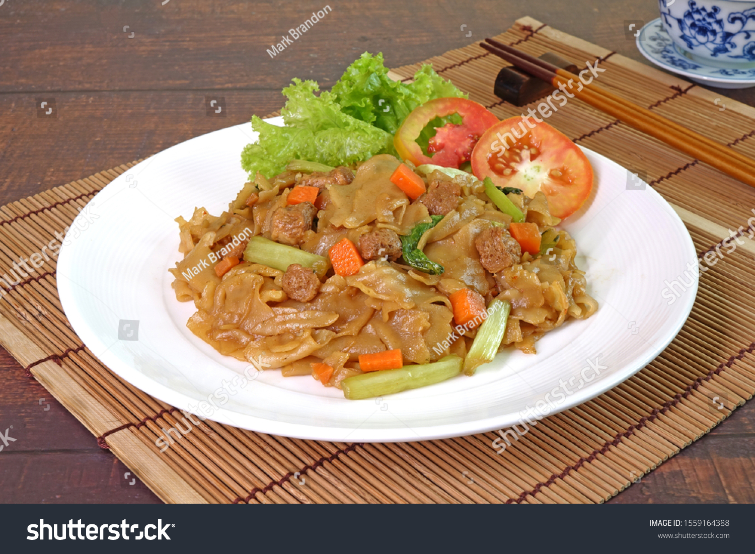 Stir fried flat noodle with black soy sauce, tofu, carrots and green vegetables. Vegetarian food for vegetarian festival. Thai style stir fry flat noodle. (Pad See Ew) Selective focus with copy space #1559164388