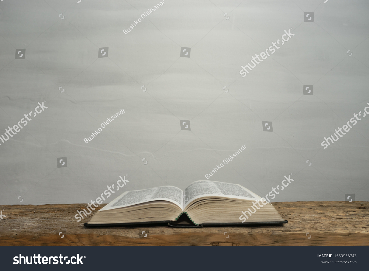 Open Holy Bible on a old wooden table and white wall background. Religion concept. #1559958743