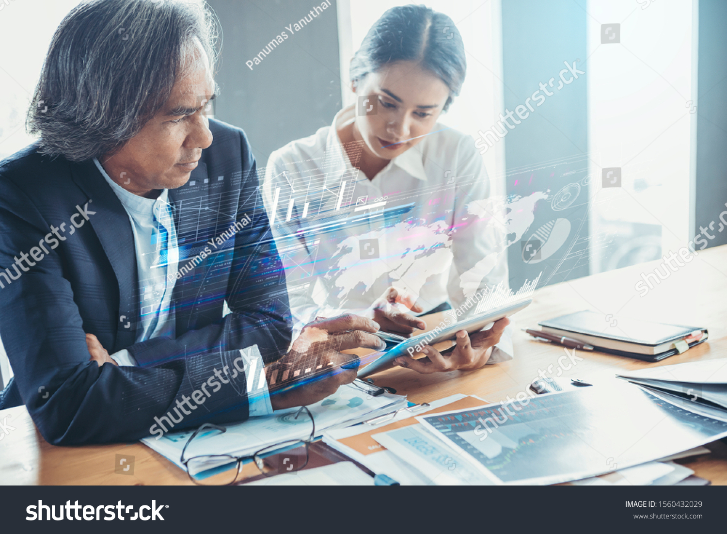 Young attractive businesswoman working with touchpad has been guided and consulting by senior colleague with visual graphic #1560432029