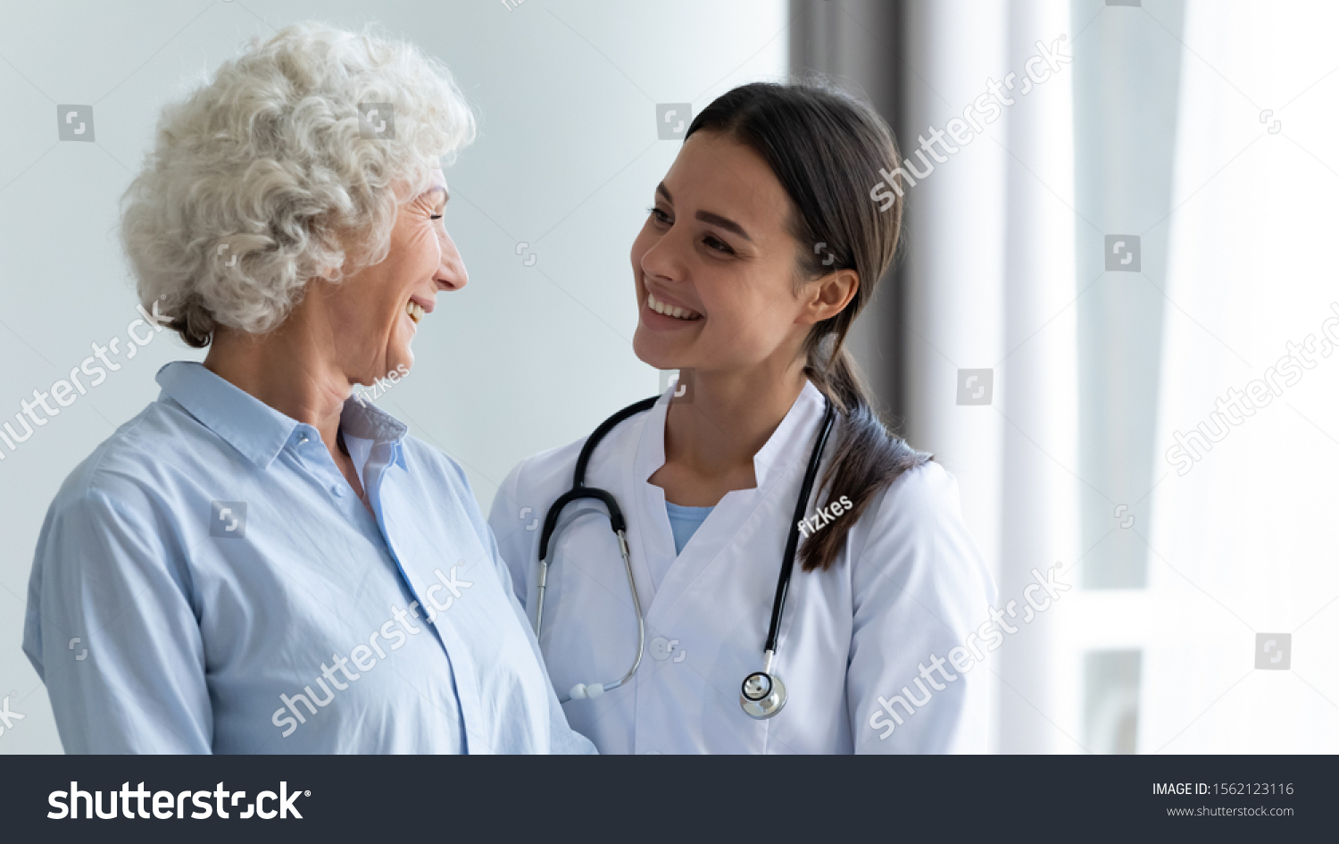 Smiling caring young female nurse doctor caretaker assisting happy senior grandma helping old patient in rehabilitation recovery at medical checkup visit, elder people healthcare homecare concept #1562123116